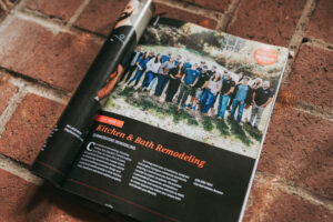 Magazine spread with a group photo outdoors and an article on kitchen & bath remodeling; orange Bethesda sticker on page.