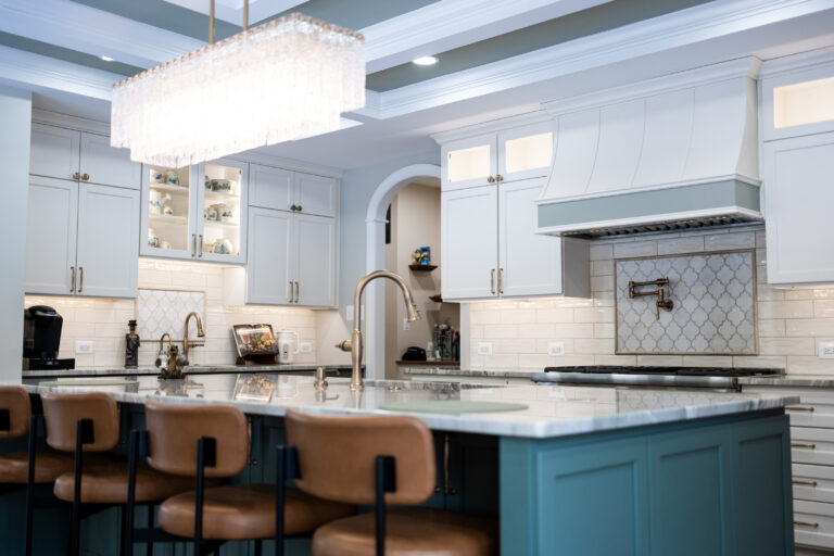 Bright modern kitchen with blue cabinets, a marble island, and a large crystal chandelier overhead