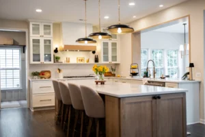 Bright modern kitchen with white cabinets, a large island, and three black-and-brass pendant lights above the bar seating area, illuminated and airy.