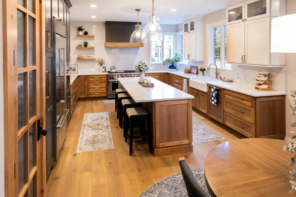 Bright kitchen with warm wood cabinets, a large central island, and stainless steel appliances under pendant lights.