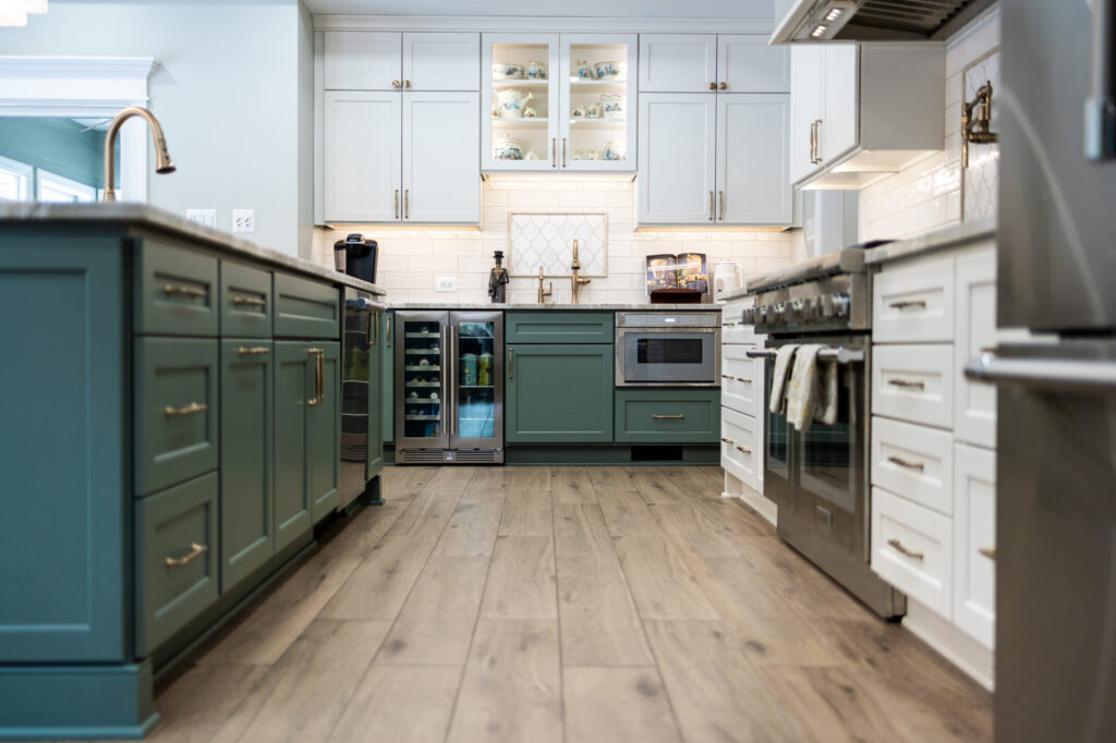 Bright modern kitchen with blue-green lower cabinets, white upper cabinets, and a light marble countertop.