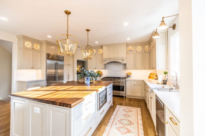 Bright white kitchen with a large central island, pendant lights, stainless steel appliances, and a patterned rug runner.